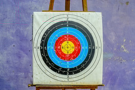 Colorful archery target on wooden easel against textured purple wall, concept of aim, focus and goal achievement. photo