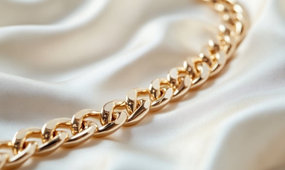 A gold chain with a gold clasp is laying on a white background photo