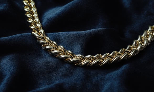 A gold chain necklace is on a blue cloth photo