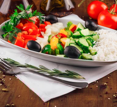 Shopska salad with feta cheese, tomatoes, cucumber and olives resting on a wooden table photo