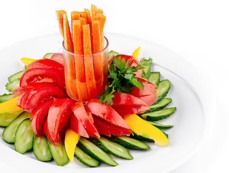 Fresh vegetables arranged on plate forming flower shape with carrots in the middle photo