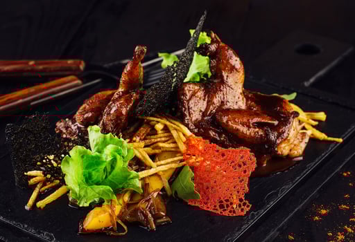 Grilled quails served on stone plate with potatoes and mushrooms photo