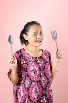 Indonesian Asian Middle Age Woman Holding SPoon and Fork, photo