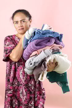 Asian Mom Weearing Daster Holding Wrinkled Clothes Laundry with Angry Face Expression photo
