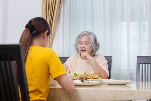 Mother and adult daughter eating meal together, Senior woman and daughter having breakfast in morning together photo