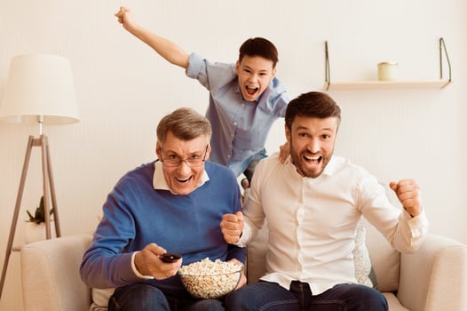 Excited Elderly Man, His Mature Son And Grandson Watching Sports On TV Shouting Celebrating Victory Sitting On Sofa Indoor photo
