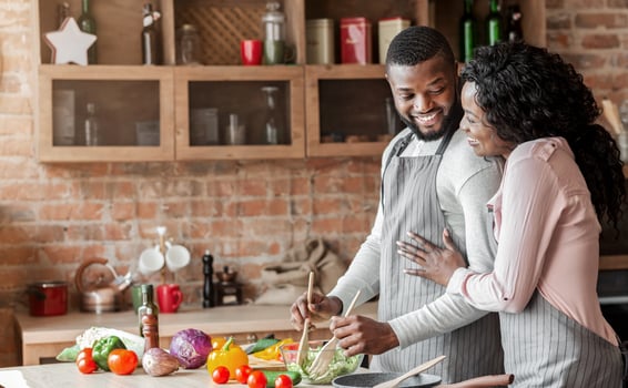Thankful happy african lady hugging her husband, cooking together at home, healthy food concept, free space photo