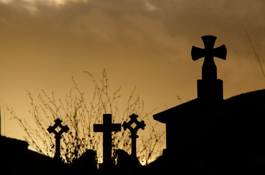 A cross and a tombstone in silhouette photo