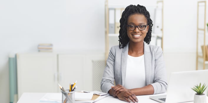 Cheerful African American professional woman working on her laptop at her desk in a modern office, copy space photo