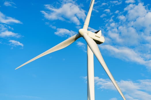 A striking white windmill stands prominently against a clear blue sky. Its blades stretch wide, harnessing wind energy to produce sustainable electricity in a picturesque landscape. photo