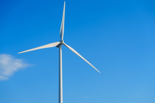 A large white wind turbine with three blades towers against a clear blue sky, symbolizing clean energy. It harnesses wind power for sustainable electricity generation, contributing to a greener future. photo