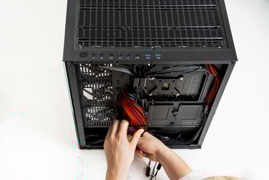 A focused individual is seen installing various hardware components into a sleek black computer case. The case is open, revealing the interior, while the persons hands adjust the components with precision. photo