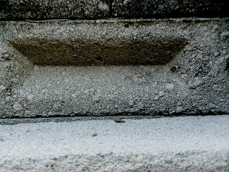 weathered concrete surface, showcasing the rough texture, cracks, and shadows created by its uneven surface. photo