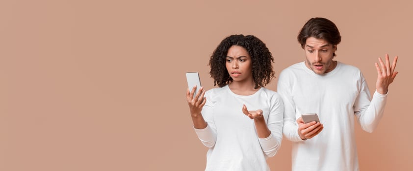 No WiFi. Disappointed interracial couple with smartphones suffering problems with internet or network connection, yellow background, panorama photo