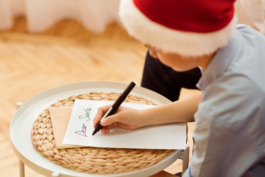Xmas Gifts Wishlist. Boy Writing Letter To Santa Claus Sitting On Sofa At Home. Selective Focus photo