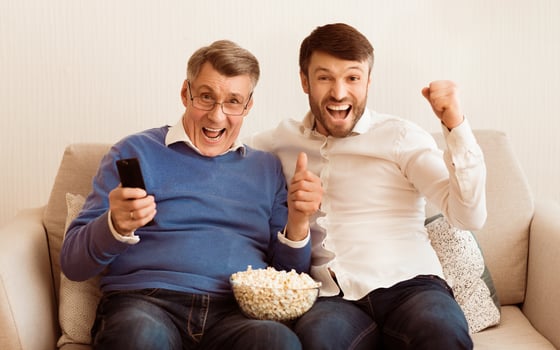 Happy Mature Man And Elderly Father Watching Sport Match On TV Shouting Celebrating Victory Sitting On Couch At Home. photo
