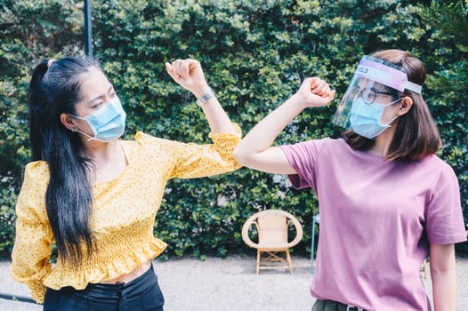 Two woman bump elbows for greeting during coronavirus epidemic. The elbow bump was suggested as an alternative way for reduce your risk of spreading or contracting the virus. photo