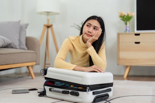 Woman Packing a Suitcase in a Modern Living Room, Preparing for Travel or Vacation, Thoughtful Expression photo