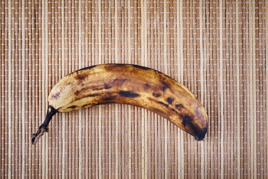 An overripe banana lies on a bamboo napkin. photo