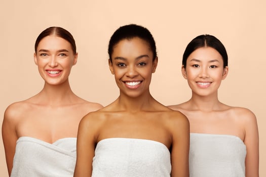 Three Attractive Women In Bath Towels Smiling At Camera Posing In Studio Over White Background. Body Care And Beauty photo