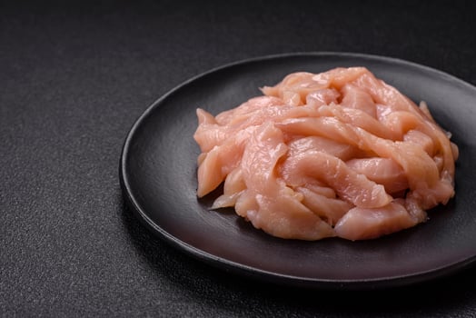Raw chicken fillet cut into strips with spices and herbs photo