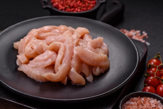Raw chicken fillet cut into strips with spices and herbs photo
