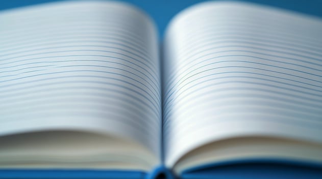 A blank notebook lies open on a blue surface, inviting creativity and ideas to flow freely photo