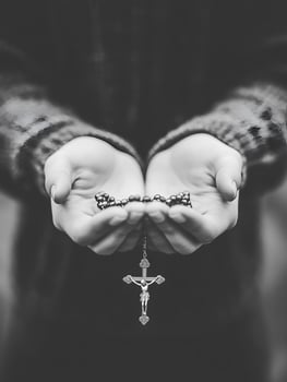 A person holds a rosary in prayer, reflecting deep faith and devotion in a serene moment photo