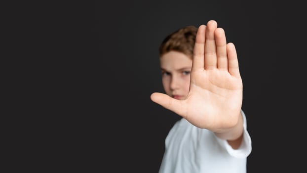 Domestic violence and child abuse. Boy showing stop gesture with his hand, gray background photo