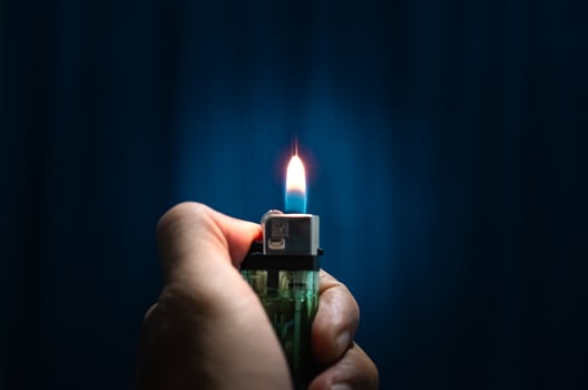 A hand is holding and lighting a lighter photo