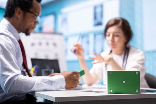 Patient and general practitioner in a consultation next to green screen on medicine box, discussing about treatment pills and supplements for wellness. Specialist pointing at medicaments. photo
