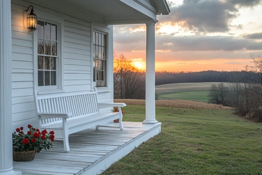 White bench sitting on front porch overlooking sunset on countryside farm photo