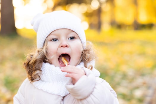 A cute pretty girl rests in the park in the middle of autumn leaves and tastes a lollipop. photo