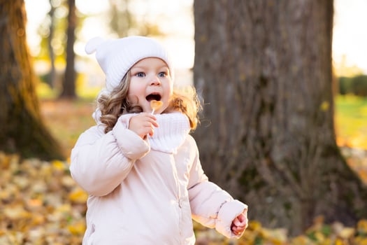 A cute pretty girl rests in the park in the middle of autumn leaves and tastes a lollipop. photo