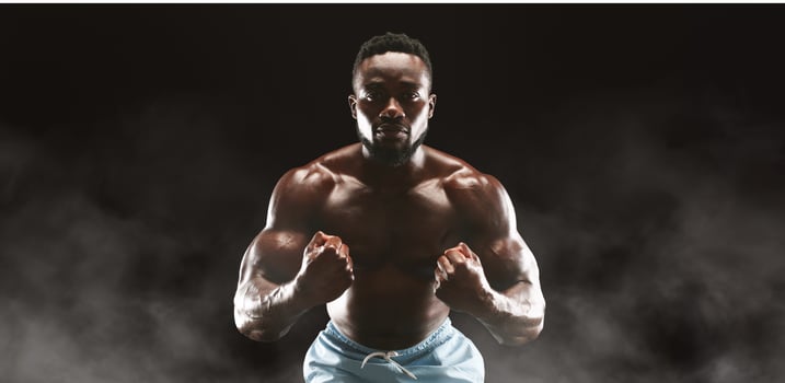 A muscular man with a determined expression poses against a dark background with smoke swirling around him. photo