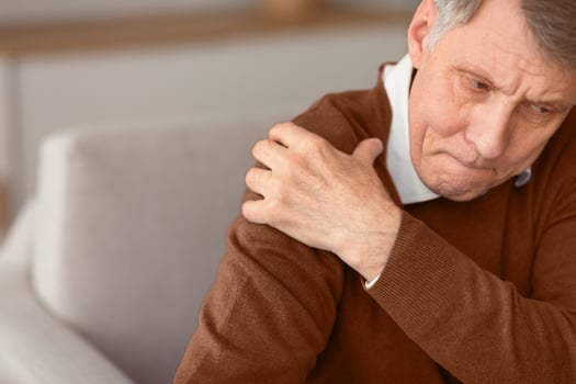 Unhappy Senior Gentleman Having Shoulder Pain Sitting On Couch At Home. Free Space, Selective Focus photo