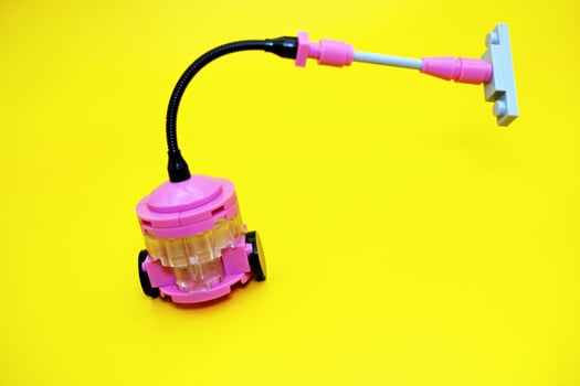 Mini vacuum cleaner toy assembled from plastic blocks. Vacuum cleaner toy isolated on yellow background. photo