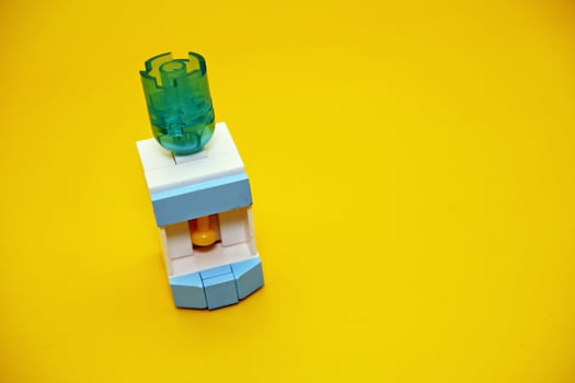 mini dispenser toy assembled from plastic blocks. dispenser toy isolated on yellow background. photo