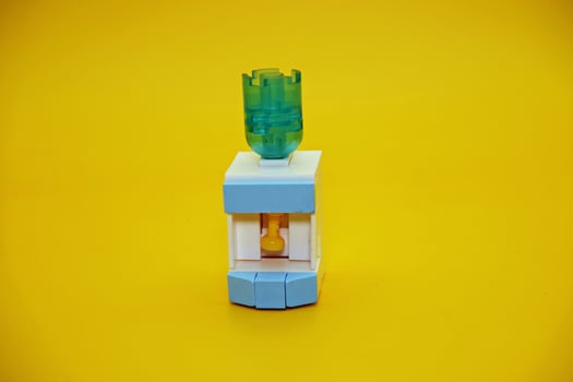 mini dispenser toy assembled from plastic blocks. dispenser toy isolated on yellow background. photo