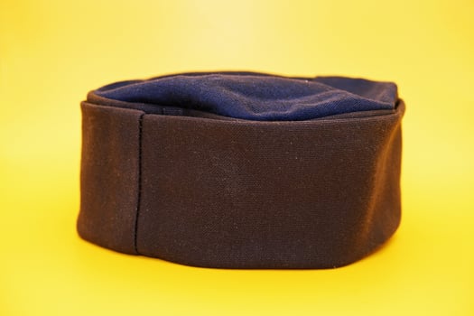 black peci isolated on yellow background. black cap used for prayer by male muslims. photo