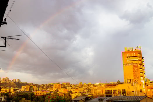 rainbow in gray cloudy sky over city district photo