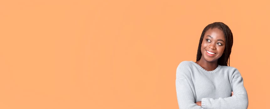 Beautiful black lady looking with interest at copy space over beige background, attracted with exciting info, panorama photo