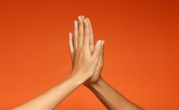African-american man and woman greeting each other with high five, clapping hands on orange background photo