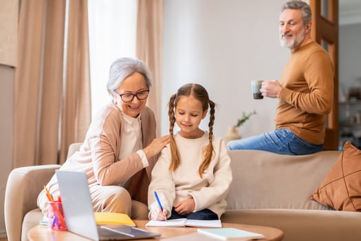 A woman is seated on a couch next to a little girl. They appear to be engaged in conversation or sharing a moment together in a living room setting. photo