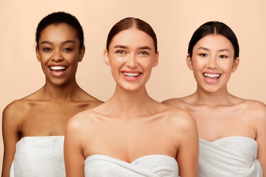 Body Care. Three Cheerful Millennial Girls In Bath Towels Smiling To Camera Posing On White Background. Studio Shot photo