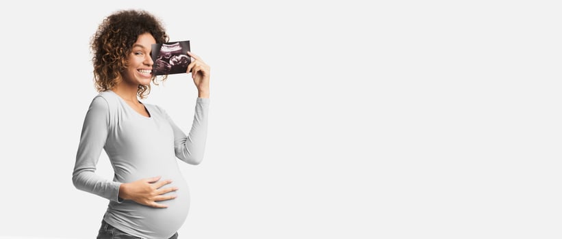 Happy pregnant woman enjoying photo of her unborn child, anticipating her future life, white background
