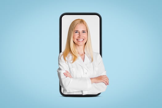 A smiling lady doctor with long blonde hair is shown on a smartphone screen. She is wearing a white lab coat and has her arms crossed. The background is a pale blue. photo