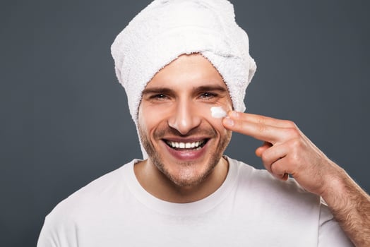Handsome cheerful man cares about beauty, smiling to camera with towel on head photo