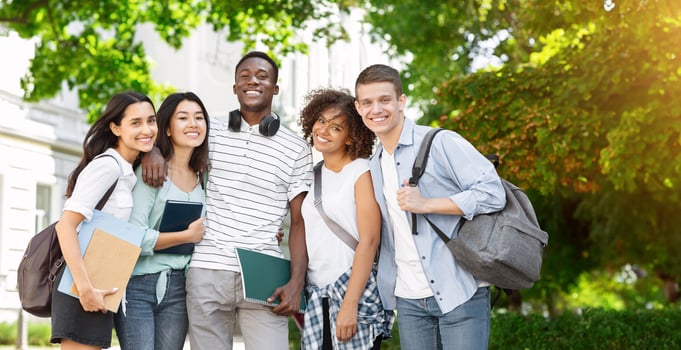 Group of international students posing in front of university, looking at camera and smiling photo