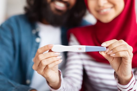 Cropped of muslim man and woman are standing together, each holding pregnancy test in their hands, closeup photo
